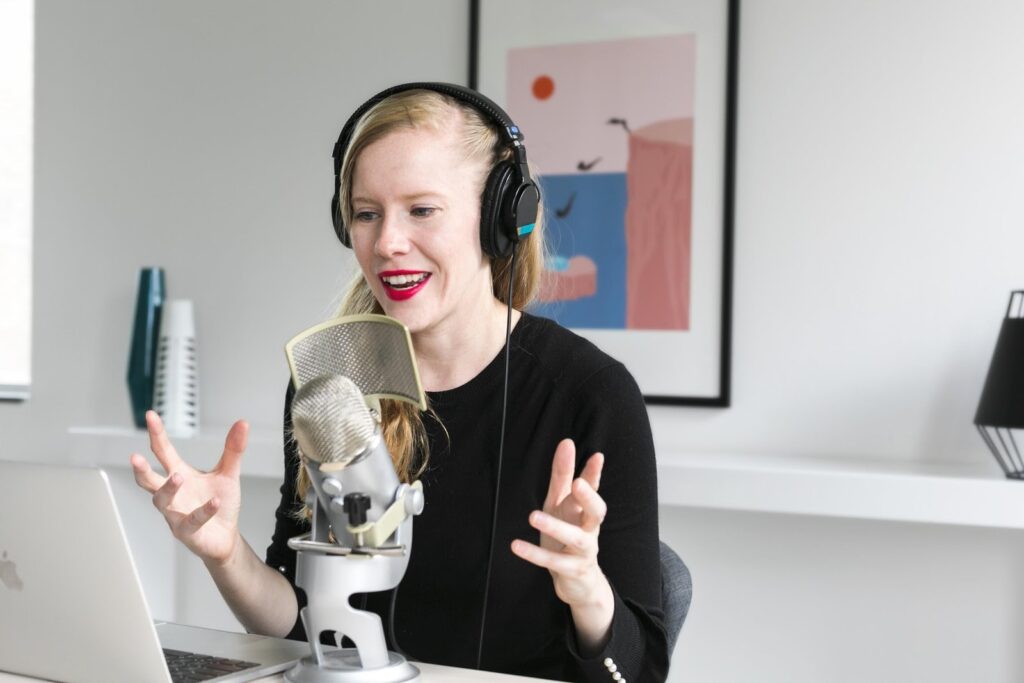 girl with headphones recording with a microphone in front of a computer